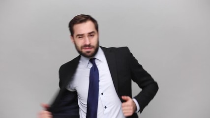 Wall Mural - Fun bearded young business man in classic black suit shirt tie posing isolated on grey background studio. Achievement career wealth business concept. Mock up copy space. Take off jacket dance rejoice