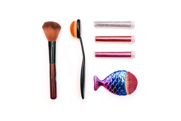 Makeup tools. Powder brushes and colored sparkles. Cosmetic accessories on a white background. Women's fashion.