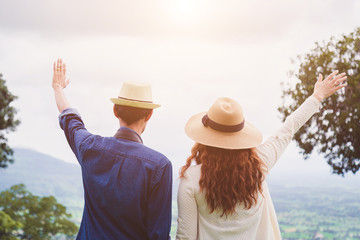 young asian traveler with camera holding hat and breathing at field of grasses and forest, wanderlust travel concept, space for text, atmosperic epic moment