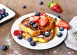 Delicious french toast with fresh fruits and maple sirup. Tasty breakfast scene or dessert with toast, strawberries, blueberries and powdered sugar.