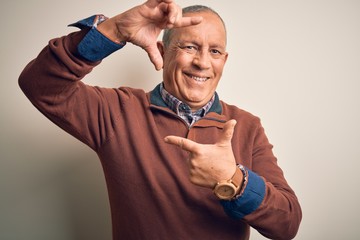 Wall Mural - Senior handsome man  wearing elegant sweater standing over isolated white background smiling making frame with hands and fingers with happy face. Creativity and photography concept.