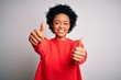 © Krakenimages.com - Young beautiful African American afro woman with curly hair wearing red casual sweater approving doing positive gesture with hand, thumbs up smiling and happy for success. Winner gesture.