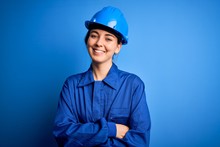 Young Beautiful Worker Woman With Blue Eyes Wearing Security Helmet And Uniform Happy Face Smiling With Crossed Arms Looking At The Camera. Positive Person.