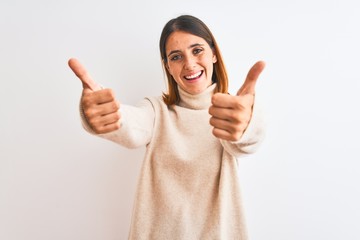 Beautiful redhead woman wearing winter turtleneck sweater over isolated background approving doing positive gesture with hand, thumbs up smiling and happy for success. Winner gesture.