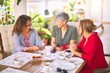 © Krakenimages.com - Meeting of middle age women having lunch and drinking coffee. Mature friends smiling happy using smartphone at home on a sunny day