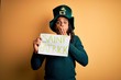 © Krakenimages.com - Young african american man wearing green hat holding banner celebrating saint patricks day cover mouth with hand shocked with shame for mistake, expression of fear, scared in silence, secret concept