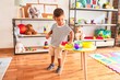 Beautiful toddler boy playing meals with plastic plates, fruits and vegetables at kindergarten