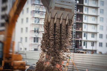 Yellow heavy excavator excavating sand and working during road works, unloading sand during construction of the new road