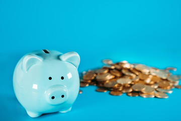 Horizontal image of a blue piggy bank standing on a white desk surface with copy space on the background.