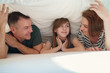 © Space_Cat - Happy family in bedroom: mother ,father and daughter under the blanket in bed at home