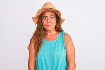 Middle age mature woman wearing summer hat over white isolated background with serious expression on face. Simple and natural looking at the camera.