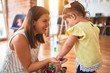 © Krakenimages.com - Young beautiful teacher and toddler playing with small building blocks toy at kindergarten