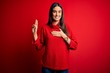 © Krakenimages.com - Young beautiful brunette woman wearing casual sweater over isolated red background smiling swearing with hand on chest and fingers up, making a loyalty promise oath