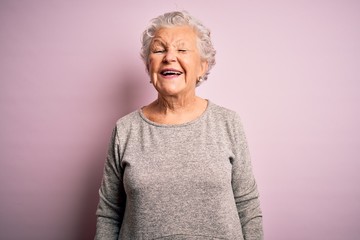 Wall Mural - Senior beautiful woman wearing casual t-shirt standing over isolated pink background winking looking at the camera with sexy expression, cheerful and happy face.