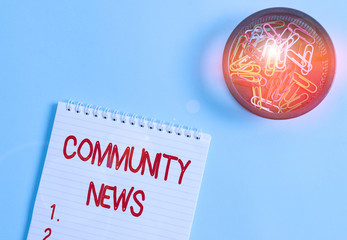 Conceptual hand writing showing Community News. Concept meaning news coverage that typically focuses on city neighborhoods Blank notebook and stationary placed above pastel colour backdrop