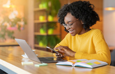 Happy black girl working online and using mobile phone