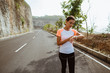 Fitness sport girl resting after intensive run walking on empty road looking at her smartwatch