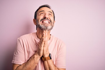 Sticker - Middle age hoary man wearing casual t-shirt standing over isolated pink background begging and praying with hands together with hope expression on face very emotional and worried. Begging.