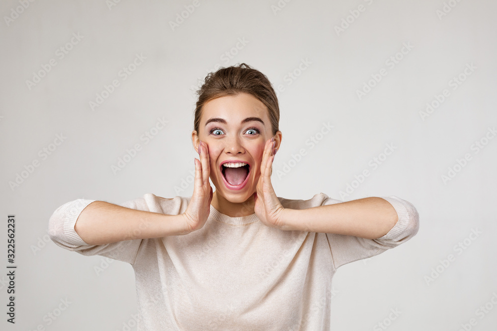 Portrait of young surprised beautiful woman screaming with shocked facial expression on gray background - obrazy, fototapety, plakaty 