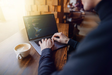 Working on laptop. Hands of business man at computer. Man works with program code. Cup of coffee near laptop.