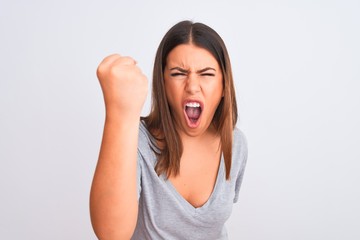 Poster - Portrait of beautiful young woman standing over isolated white background angry and mad raising fist frustrated and furious while shouting with anger. Rage and aggressive concept.