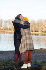 Wall Mural - Two women hugging near the lake