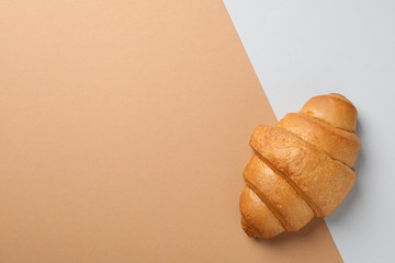 Freshly baked croissant on two tone background, top view