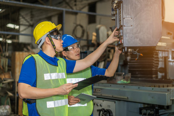 Industrial engineers in safety uniforms wearing yellow safety helmets are inspecting work by tools.  and on the job training he works in industrial machinery.