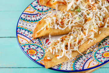 Mexican fried empanadas with cabbage and sauce on turquoise background