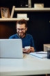© chika_milan - Young smiling handsome caucasian freelancer sitting in his modern home office and holding cup of coffee.