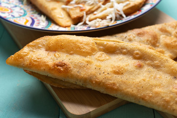 Mexican fried empanadas with cabbage and sauce on turquoise background