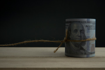 Close up of role money dollar tied with rope on black background.