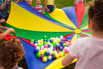 Canvas Print - Happy kids waving rainbow parachute full of balls