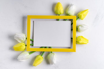 Canvas Print - YellowTulips with blank picture frame on white marble background, copy space