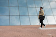 © Cavan Images - Businessman is walking with a glazed building in the back