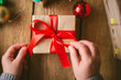 © Cavan Images - Woman wrapping christmas gifts on wooden background