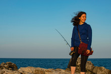 Woman In Blue Fly Fishing On A Windy Day At The Coast Of Maine