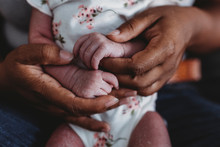 Ethnic Female Hands Holding Tiny Waxy Hands Of Multiracial Newborn