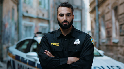 Portrait attractive young man cops stand near patrol car look at camera enforcement happy officer police uniform auto safety security communication control policeman close up slow motion