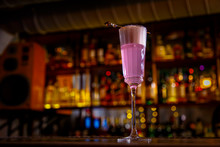 A Purple Sauer Cocktail In A Tall Glass With Foam Stands On The Bar