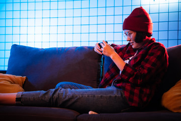 Pretty young woman using mobile phone playing online game at home