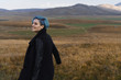 Beautiful smiling girl with blue hair in a black coat on a background of an autumn meadow and mountains