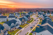 Aerial sunset panorama of luxury real estate development single family house neighborhood curving street with dramatic sky in Maryland USA