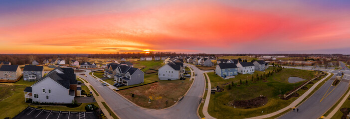 Aerial sunset view of upscale American new residential neighborhood with single family homes with orange, red, yellow sky