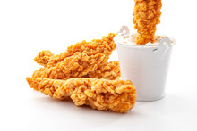 Eating Fast Food And Protein High Diet Concept With Golden Breaded Chicken Strips And One Crispy Strip Being Dipped In A Metal Bucket Of Ranch Dressing Sauce Isolated On White Background