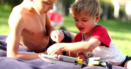 Wall Mural - Candid brothers siblings playing with toys outside