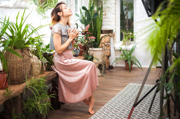 Woman and a mug in her hands. Girl in the interior of the living room in the Scandinavian style. Winter garden with flowers. Flower care concept. Urban jungle.