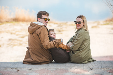 Wall Mural - young beautiful family sitting at beach with view lake