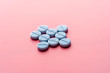 Close-up of bkue pills lie on a pink surface