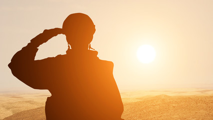 Silhouette Of A Solider Saluting Against the Sunrise in the desert of the Middle East. Concept - armed forces of UAE, Israel, Egypt